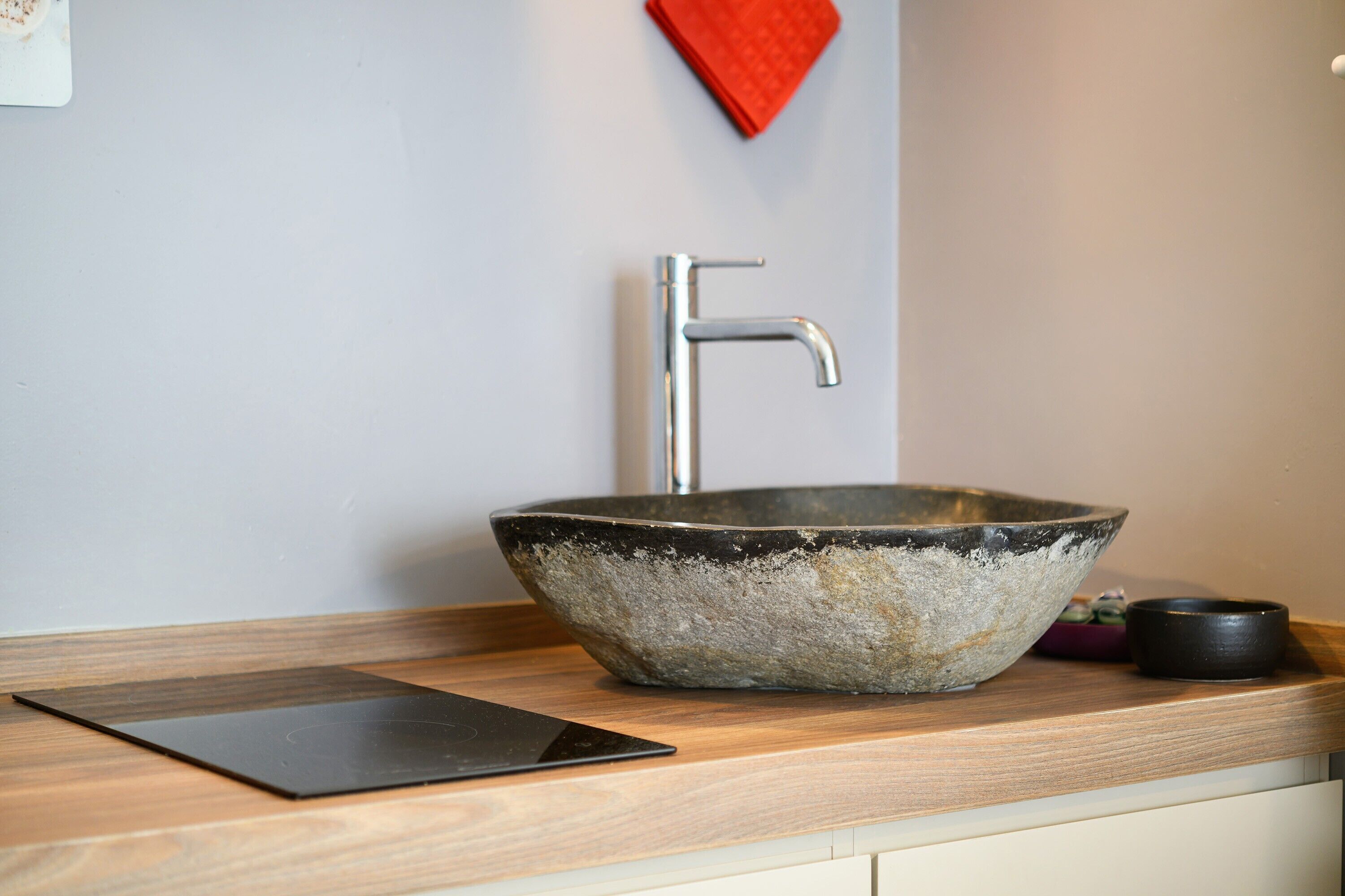 A modern kitchen with a large ceramic sink, a faucet, and a tablet on the counter.