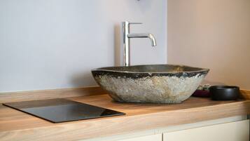 A modern kitchen with a large ceramic sink, a faucet, and a tablet on the counter.