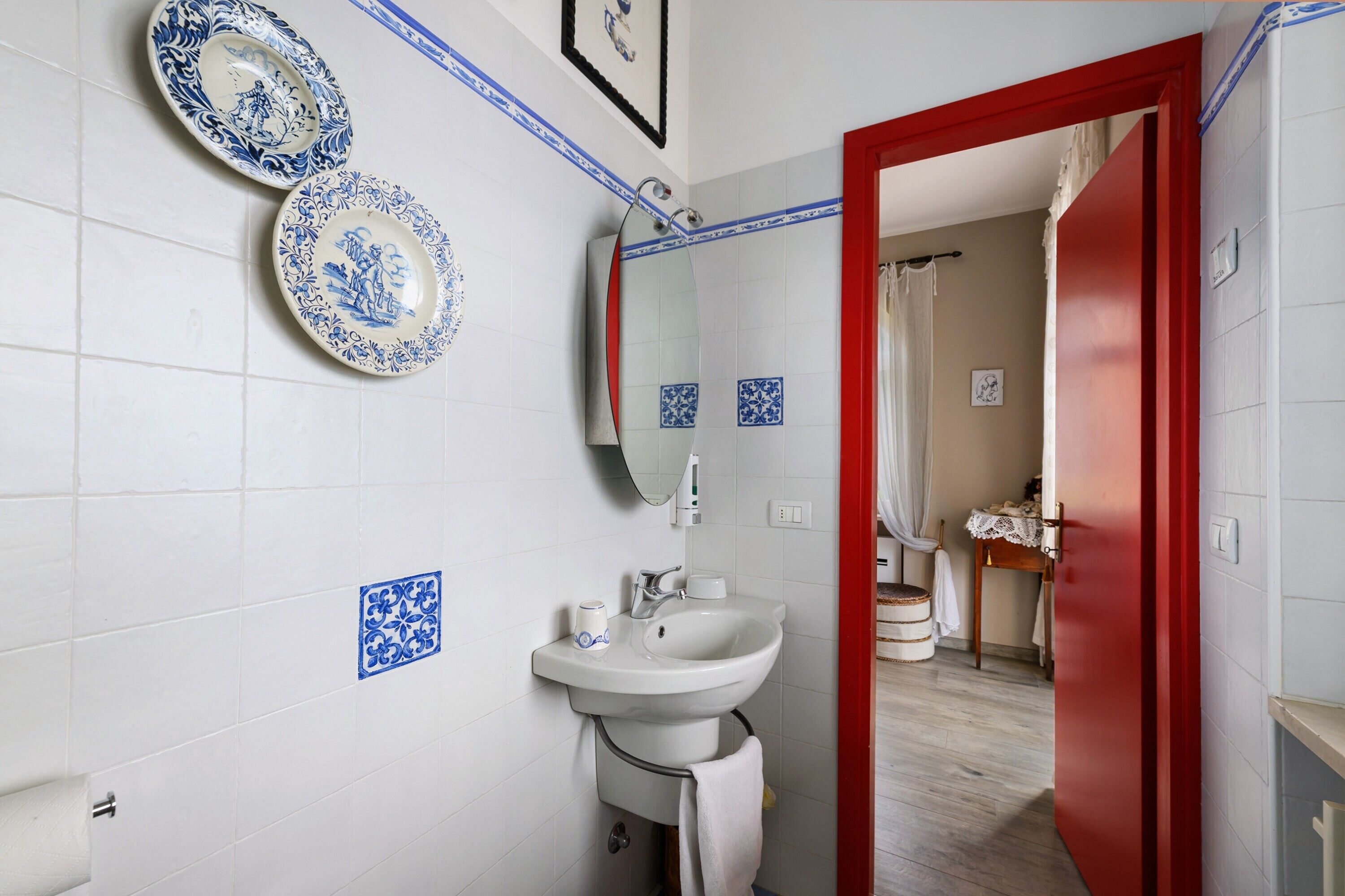 Casa de banho com lavatório, espelho e pratos decorativos na parede.