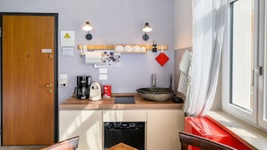 A compact kitchen with a coffee maker, sink, and a large bowl.