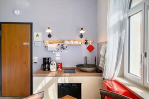 Pieni, käytännöllinen keittiö, jossa on kahvinkeitin, pesuallas ja suuri kulho.