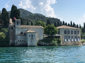 A historic building with a bell tower, a statue, and a view of the water.
