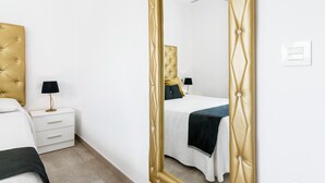 A bedroom with a bed, bedside tables, a mirror, and a wardrobe. - Modern, with roof terrace and very close to the beach - Apartamento La Perla (Conil de la Frontera)