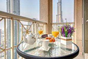 Un balcon avec une table préparée pour le petit-déjeuner, comprenant des croissants, du jus d’orange et une théière.