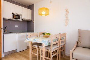 A compact kitchen with a microwave, a dining table with chairs, a hanging light fixture, and a wall-mounted star decoration. - Apartment Close to the Beach with Pool Access, Private Terrace, Air Conditioning and Wi-Fi (Canyamel)