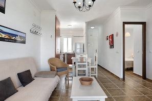 A living room with a sofa, chairs, a table, and a chandelier.