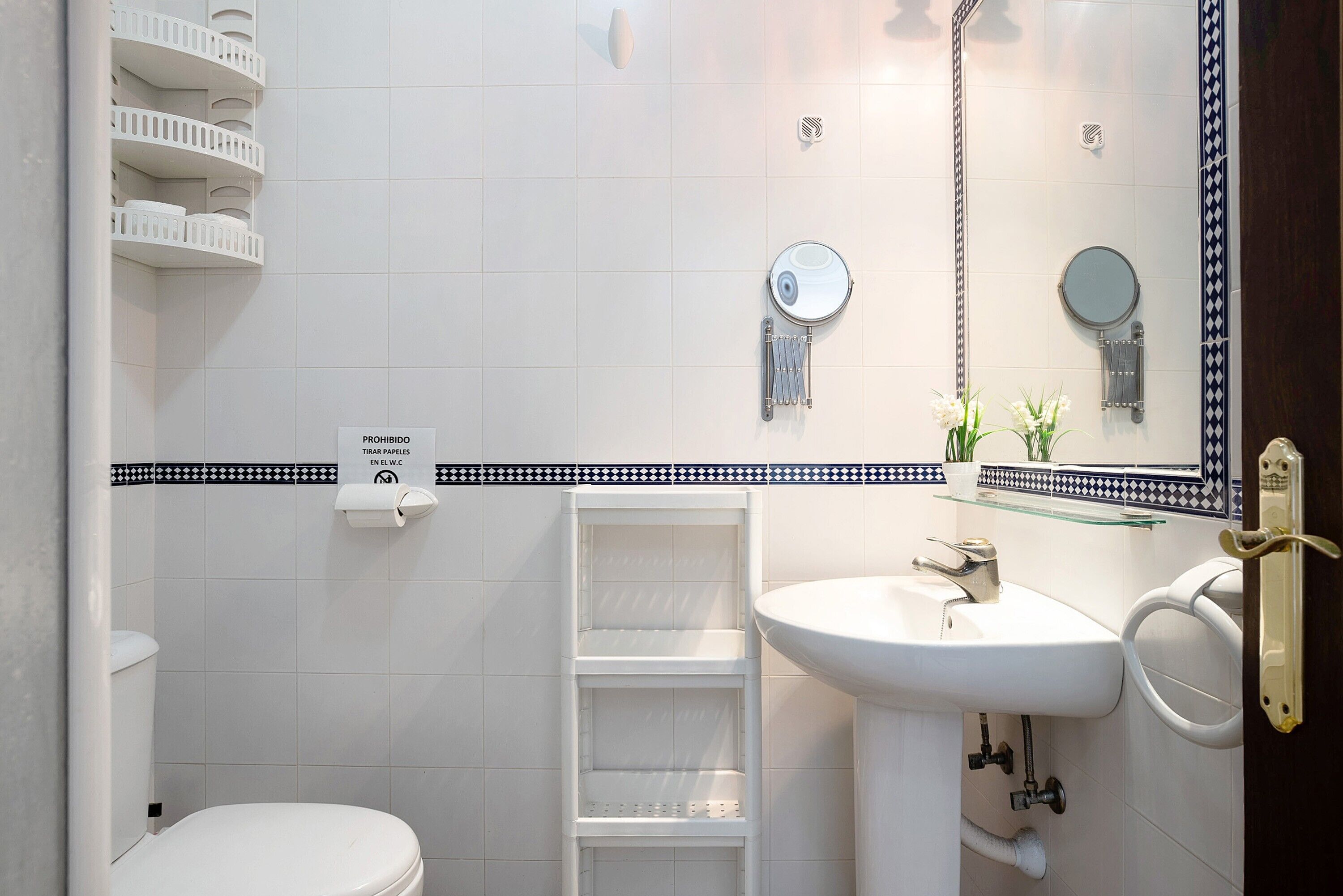 Ein Badezimmer mit Toilette, Waschbecken, Spiegel und Ablage für Pflegeprodukte.