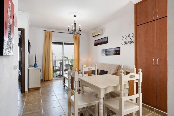 A dining area with a white table and chairs, a chandelier, and a wooden wardrobe.