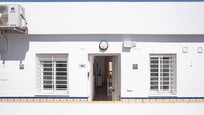 Un edificio bianco con un portale centrale, due finestre dotate di inferriate bianche e un condizionatore GREE montato sulla parete.