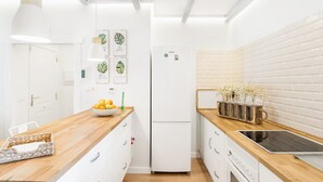 Eine moderne Küche mit weißen Schränken, einer Holz Arbeitsplatte, einem Backofen und einem Kühlschrank.