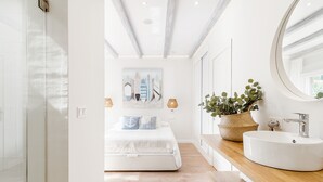 Ein modernes Badezimmer mit einem Holzwaschtisch, einem runden Spiegel und einem Blumentopf.