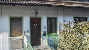 A building with a green-framed door, a number '22' above it, and a small porch area with a green railing. - Apartment “Mansarda tra le Dolomiti di Brenta" with Mountain View & Balcony (Bocenago)