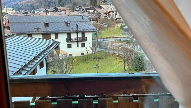A balcony with a view of a village, a mountain, and a building with a sloped roof. - Apartment “Mansarda tra le Dolomiti di Brenta" with Mountain View & Balcony (Bocenago)