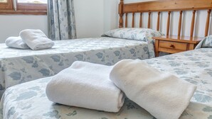 Een tweepersoonsbed met bloemenbeddengoed, een houten hoofdbord en een nachtkastje.