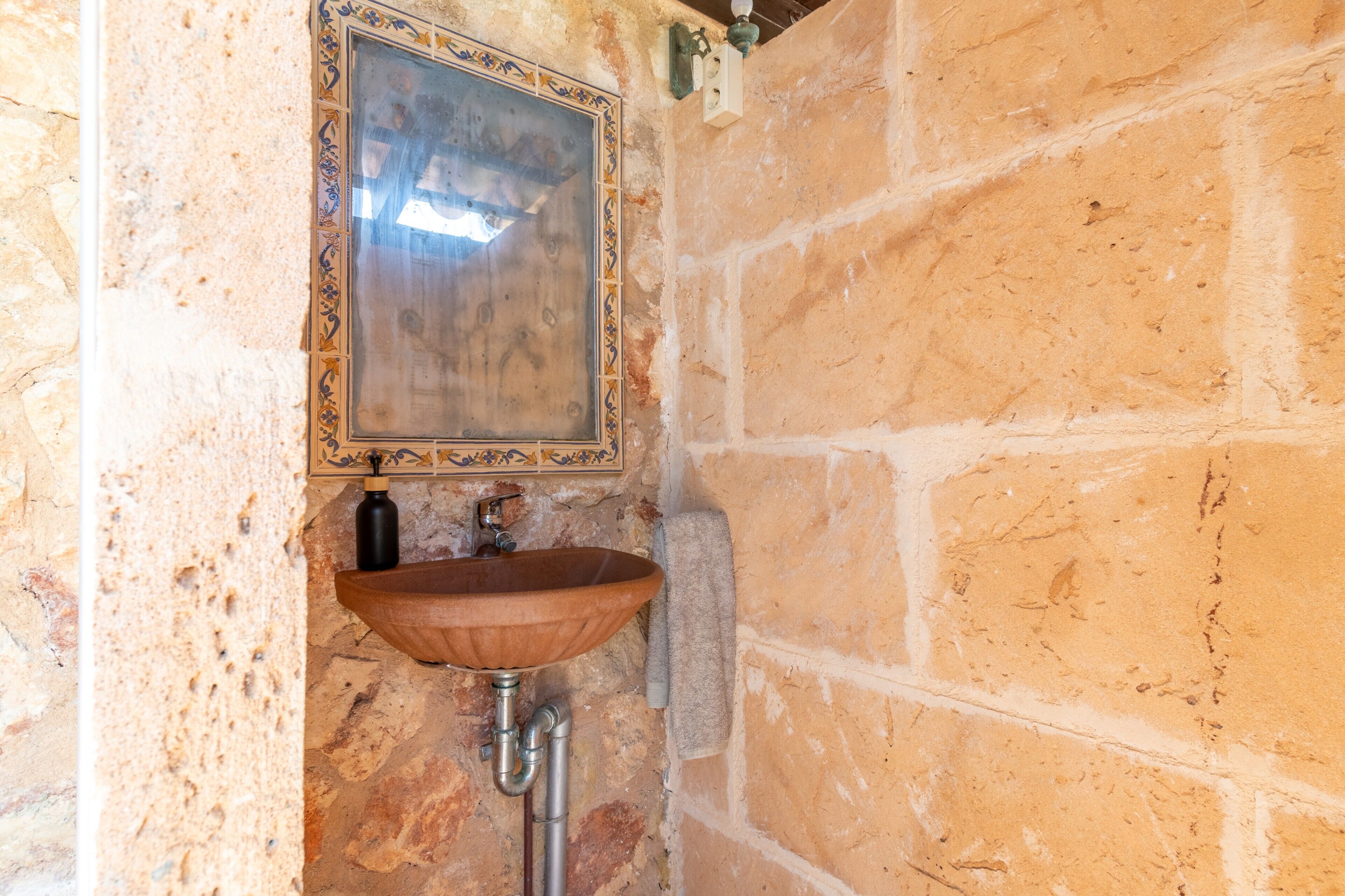 A stone wall, a wooden sink, and a mirror with a decorative frame.