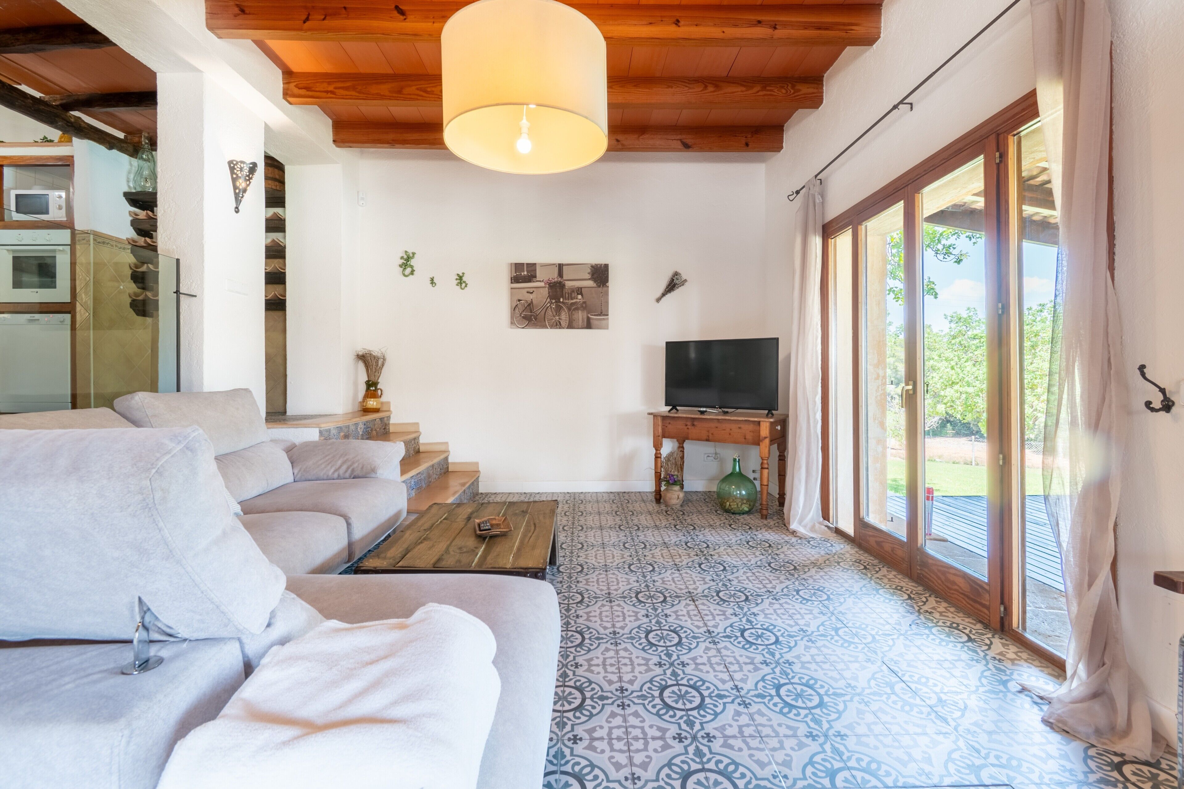Un salon avec un canapé, un téléviseur, une table en bois et un sol à motifs.