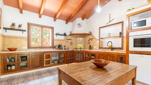 A kitchen with wooden cabinets, a wooden table, and a hanging light fixture.