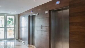 Een modern elevatorruimte met een gepolijste marmeren vloer en een wand bekleed met houten panelen.
