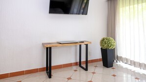 A modern room with a flat-screen TV mounted on the wall, a wooden table with a tray, and a potted plant.
