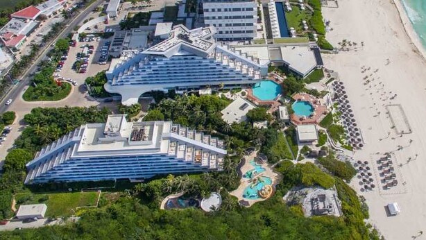 An aerial view of a resort with multiple buildings, a beach, and a pool area.