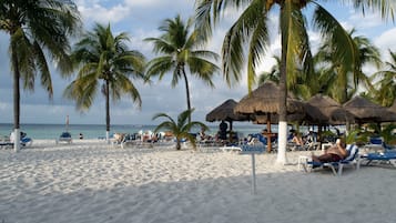 En la playa, playa de arena blanca, camastros y toallas de playa