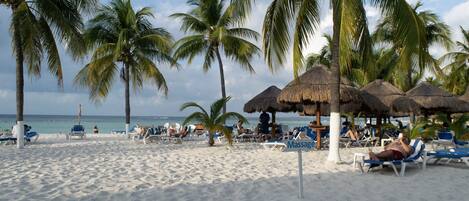 En la playa, playa de arena blanca, camastros y toallas de playa