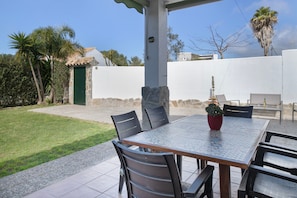 Un patio con una mesa y sillas, una planta en maceta y un muro de piedra.