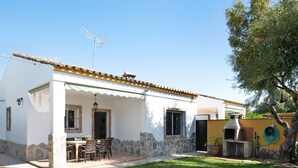 A house with a patio, a stone wall, a chimney, and a garden.