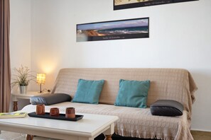 A cozy room with a sofa, a table with mugs, a lamp, and a framed picture on the wall.