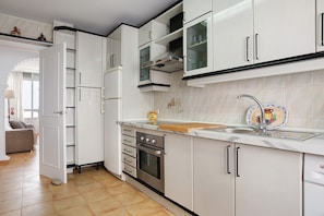 A modern kitchen with white cabinets, a stainless steel oven, and a sink with a decorative plate.