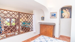 A bedroom with a bed, wooden cabinet, and a view through a lattice window.