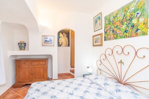 Une chambre à coucher avec un lit, une armoire en bois, un tableau et une tête de lit en métal.