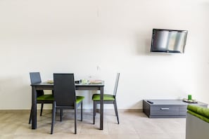 A modern room with a dining table, chairs, a TV, and a small cabinet.