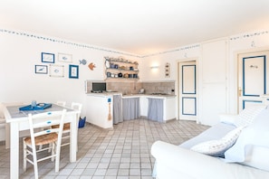 Una cocina compacta con comedor, una pequeña isla y un espacio de estar con sofá.