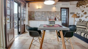 A dining area with a table, chairs, and a view through an open door. - Rural Stone Cottage "Estudio Pu" with Volcano View, Garden & Wi-Fi (Vegueta Lanzarote)