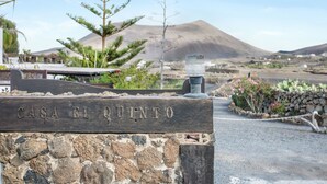 A stone wall with 'CASA EL QUINTO' engraved, a mountain in the background, and a clear sky. - Rural Stone Cottage "Estudio Pu" with Volcano View, Garden & Wi-Fi (Vegueta Lanzarote)