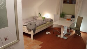 Une chambre à coucher avec un lit, un bureau, une chaise et une fenêtre avec des stores.