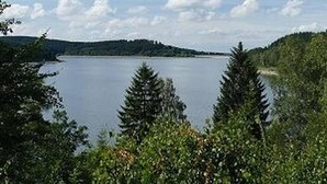 Un lac entouré d’une forêt dense et de collines.