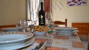 A dining table set with plates, glasses, a bottle, and a bowl of snacks. - Central holiday home with terrace and garden; parking available (San Foca)