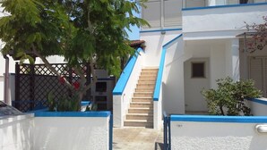 A white building with blue trim, a staircase, and a small window. - Central holiday home with terrace and garden; parking available (San Foca)