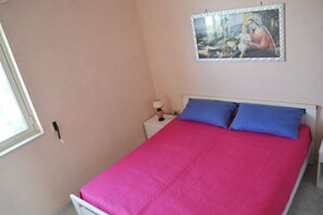 Une chambre à coucher avec un lit, une table de chevet, une lampe et un tableau accroché au mur.
