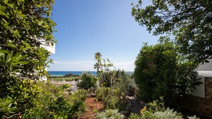 Ein Garten mit einem Kiesweg, verschiedenen Pflanzen und Blick auf das Meer.