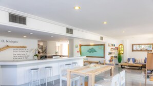 Une cuisine moderne avec des meubles blancs, un îlot central en bois doté de tabourets et une grande fenêtre offrant une belle vue.