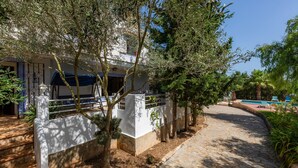 A pathway leading to a building with a pool, surrounded by trees and a stone wall. - In the country with pool - Villa Can Garba (Felanitx)