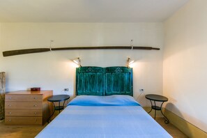 Un dormitorio con cama, cómoda, dos mesitas pequeñas y cabecera verde.