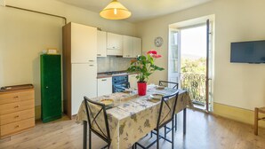 Una cocina compacta con una mesa de comedor, sillas, una planta en maceta y un televisor en la pared.