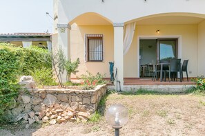 Una casa con un muro in pietra, un patio con sedie e un tavolo.