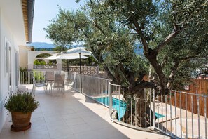 An outdoor patio with a pool, a table and chairs, and a large tree. - Town house with pool near the beach – Villa Jodie (SOLLER)