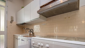 A kitchen with white cabinets, a stove, and a kettle. - Lovely little house a few meters from the beach of the romantic Manerba (Manerba)