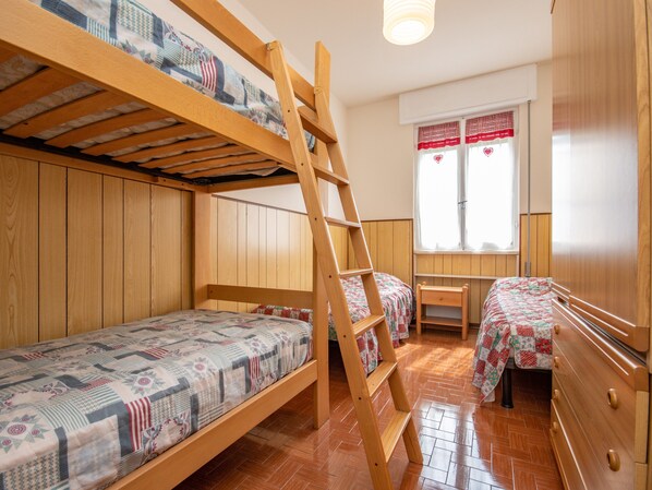 Una camera del dormitorio con letti a castello, una scala in legno, un tavolino e una finestra con tende.